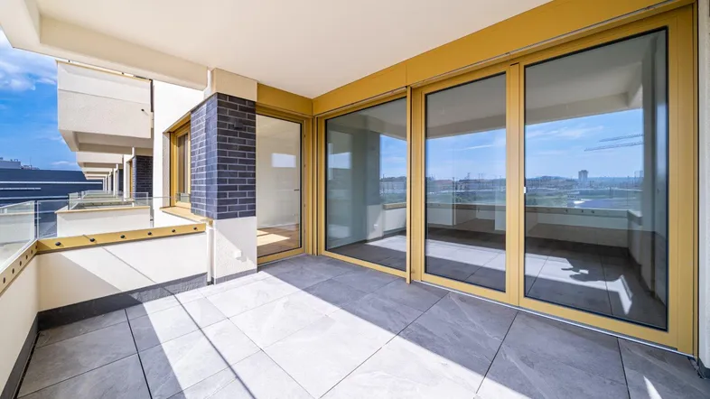Geräumiger Balkon mit Fliesenboden und Glasgeländer, bietet einen weiten Blick auf die Umgebung.