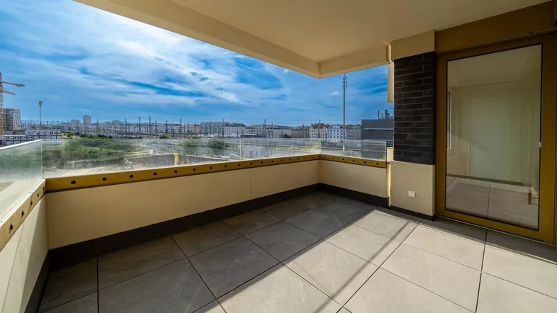Geräumiger Balkon mit Fliesenboden und Glasbrüstung, bietet einen weiten Blick auf die Stadt.