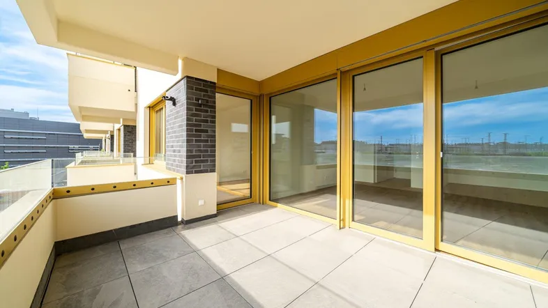 Geräumiger Balkon mit Fliesenboden und Glasgeländer, bietet einen weiten Blick auf die Umgebung.