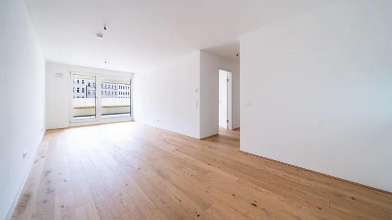 Helles, geräumiges Wohnzimmer mit modernem Parkettboden und Zugang zu einem sonnigen Balkon.