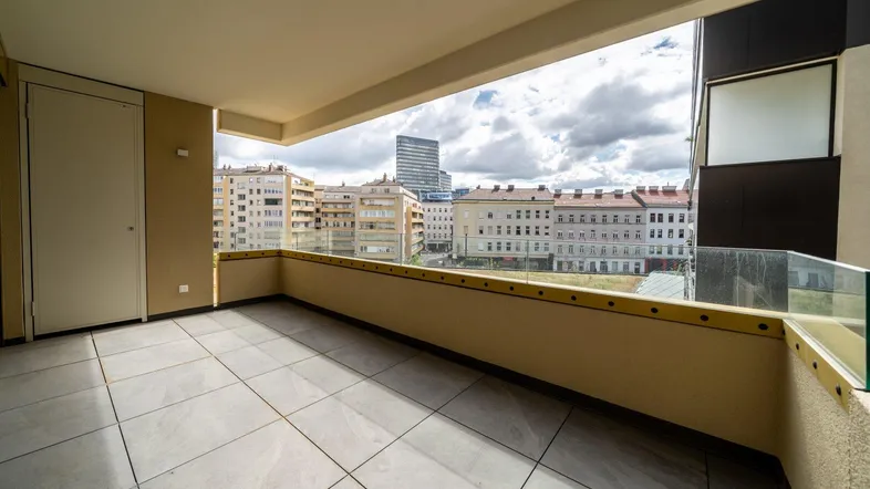 Geräumiger Balkon mit Fliesenboden und weitem Blick über die Stadt und umliegende Gebäude.