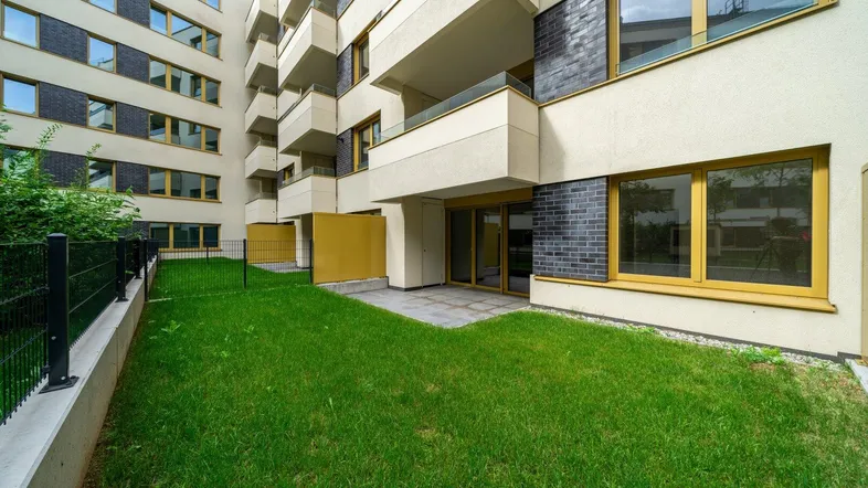 Blick auf die moderne Gebäudefassade mit privatem Gartenbereich und Terrasse im Erdgeschoss.