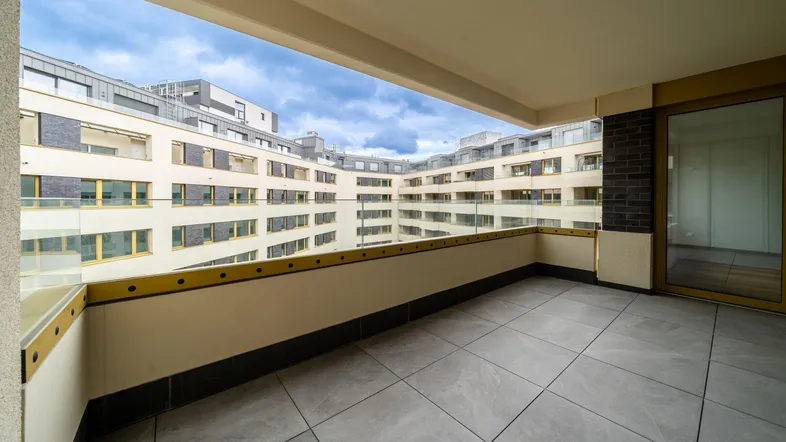 Geräumiger Balkon mit Fliesenboden und Blick auf die umliegenden modernen Gebäude des Neubaus.