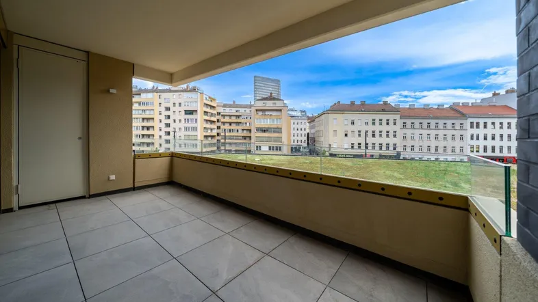 Geräumiger Balkon mit Fliesenboden und Glasgeländer bietet einen weiten Blick über die Stadt.