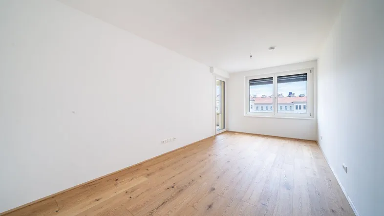 Helles Zimmer mit Parkettboden und Zugang zu einem Außenbereich, ideal als Wohn- oder Schlafzimmer.