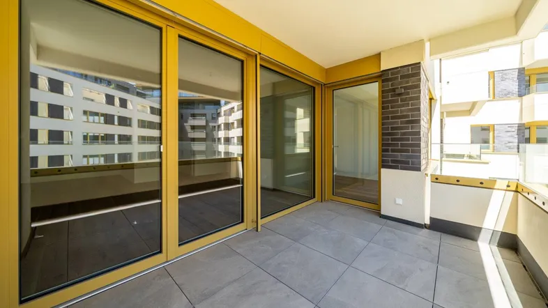 Geräumiger Balkon mit Fliesenboden und großen Glasschiebetüren, ideal für entspannte Stunden im Freien.