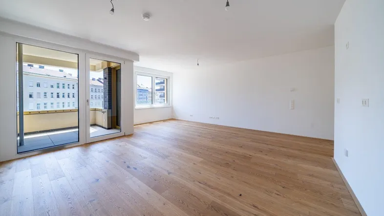 Heller, leerer Raum mit Parkettboden und Zugang zu einem Balkon, ideal für Wohn- oder Essbereich.