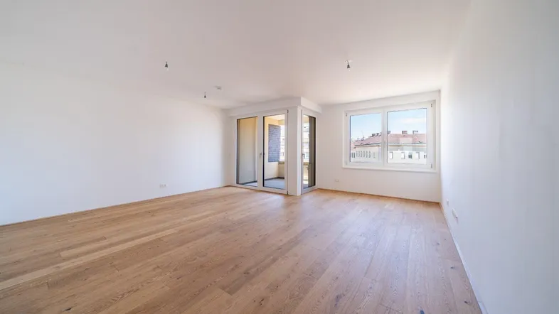 Helles und geräumiges Wohnzimmer mit neuem Parkettboden und Zugang zum Balkon.