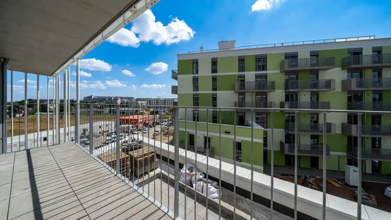 Geräumiger Balkon mit Fliesenboden und Blick auf die umliegenden Gebäude und die Baustelle.