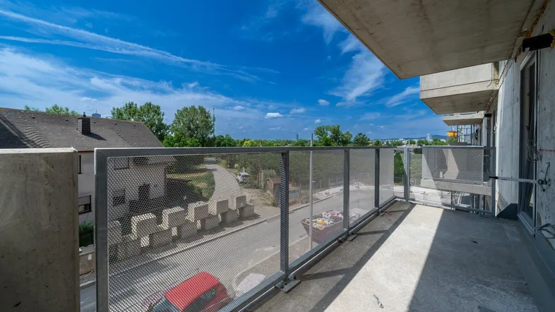 Geräumiger Balkon mit Metallgeländer und weitem Blick über die Umgebung und den Himmel.