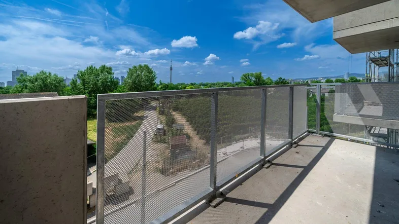 Geräumiger Balkon mit Metallgeländer und weitem Blick über die Stadt und ins Grüne.