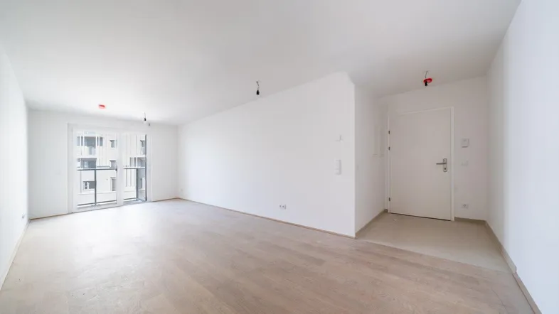 Helles, leeres Zimmer mit weiß gestrichenen Wänden und hellem Holzfußboden, bereit zum Einzug.