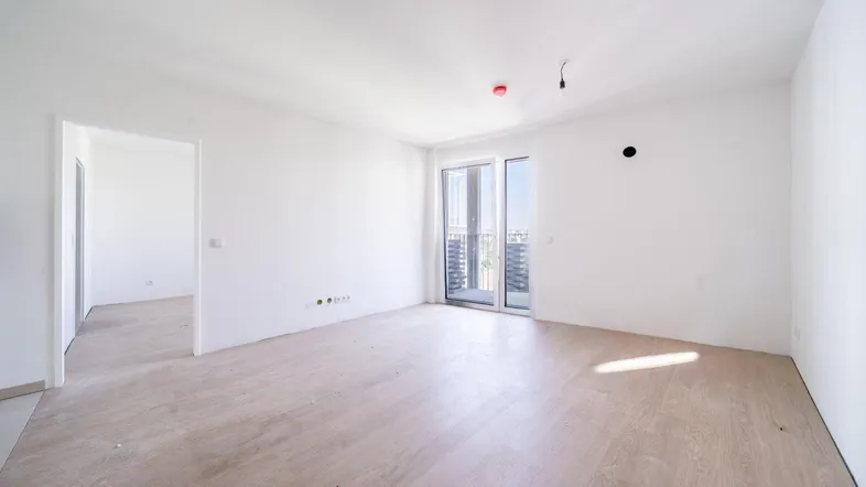 Helles, unmöbliertes Zimmer mit Parkettboden und Zugang zu einem Balkon, bereit zur individuellen Gestaltung.