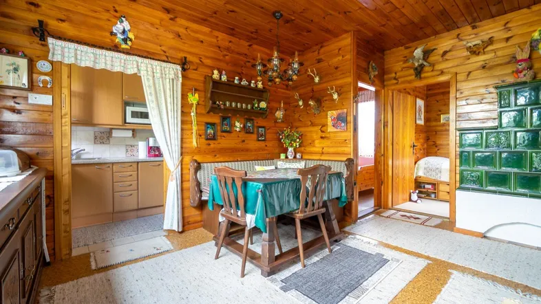 Gemütlicher Wohn-Essbereich mit Holztäfelung, traditionellem Kachelofen und rustikalen Möbeln.