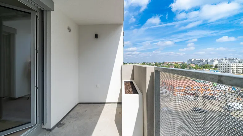 Heller Balkon mit Metallgeländer und Blick auf die umliegende Stadtlandschaft.