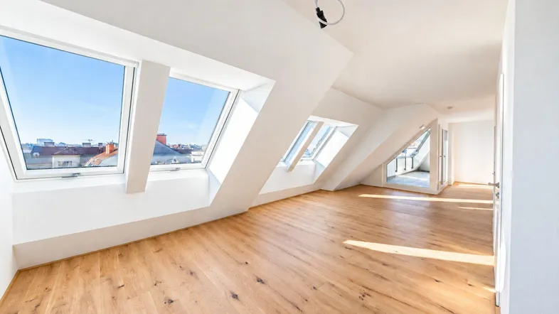 Heller Dachgeschossraum mit großen Dachfenstern und Holzboden, bietet viel natürliches Licht und Weitblick.