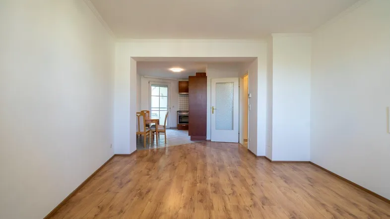 Helles Wohnzimmer mit Laminatboden und offenem Zugang zum Essbereich.