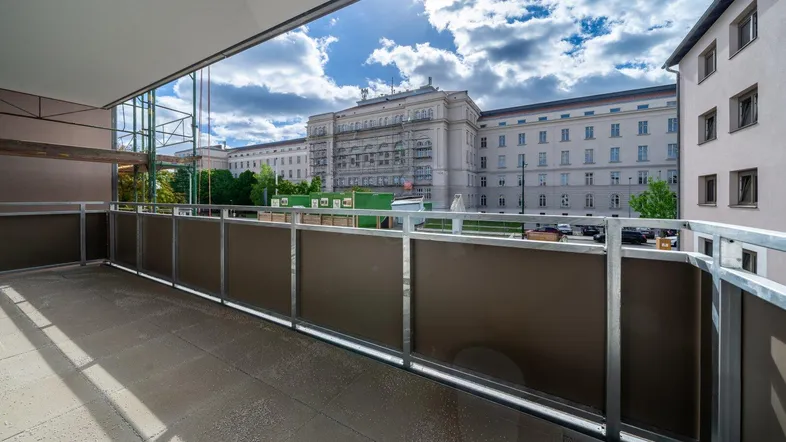 Geräumiger Balkon mit Blick auf ein großes Gebäude und den blauen Himmel.