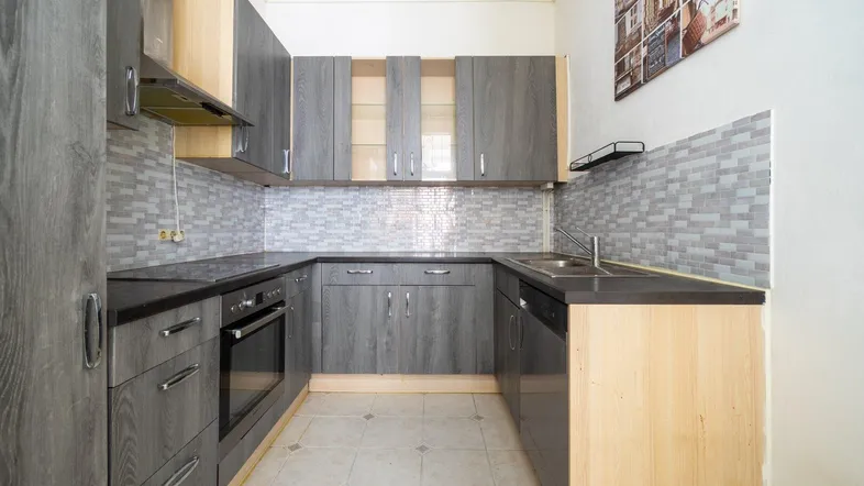 Moderne Küche mit grauen Holzfronten, dunkler Arbeitsplatte und gefliestem Fliesenspiegel.