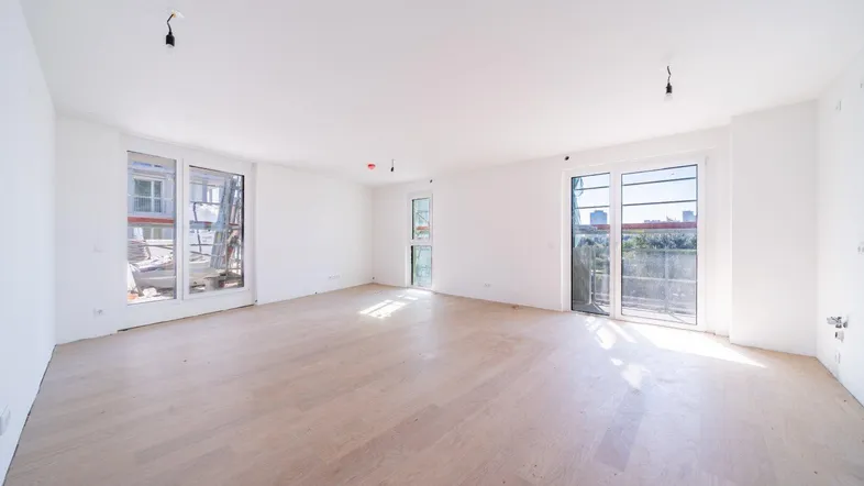 Helles, leeres Zimmer mit großen Fenstern und hellem Holzfußboden, bereit für die individuelle Gestaltung.