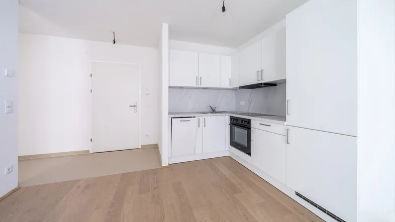 Moderne Einbauküche mit weißen Schränken und integrierten Geräten in einem offenen Wohnbereich.
