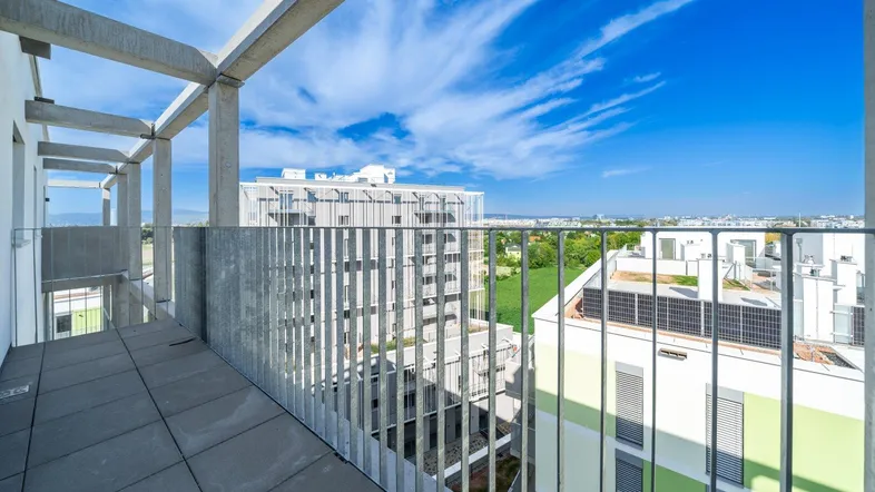Geräumiger Balkon mit Fliesenboden und weitem Blick über die umliegenden Gebäude und Grünflächen.