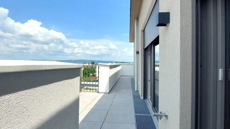 Lange, schmale Dachterrasse mit Fliesenboden und weitem Blick in die grüne Landschaft.