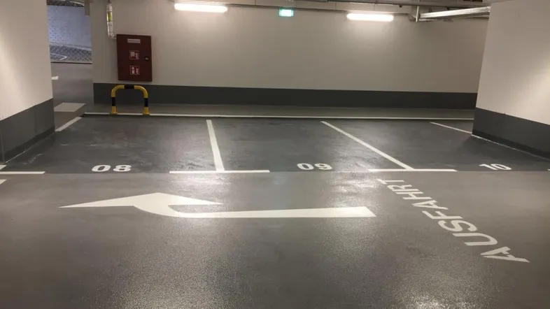 Leere Parkplätze in einer Tiefgarage mit klarer Beschilderung und guter Beleuchtung.