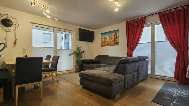 Geräumiger Wohn- und Essbereich mit Holzboden, bequemer Couch und Zugang zur Terrasse.