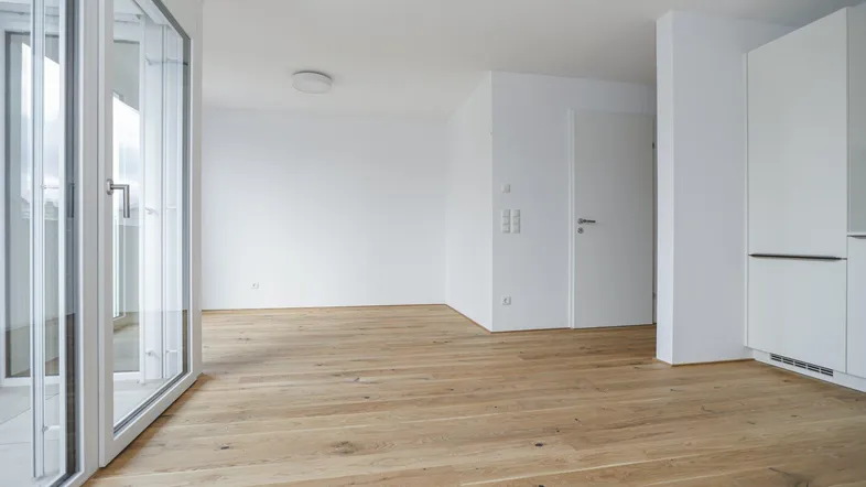 Heller, leerer Raum mit großen Fenstern und Holzboden, bereit zur individuellen Gestaltung.