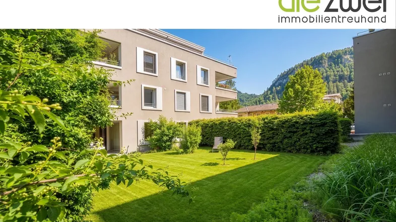 Gepflegter Gartenbereich mit Rasenfläche und Hecke vor der modernen Wohnanlage.