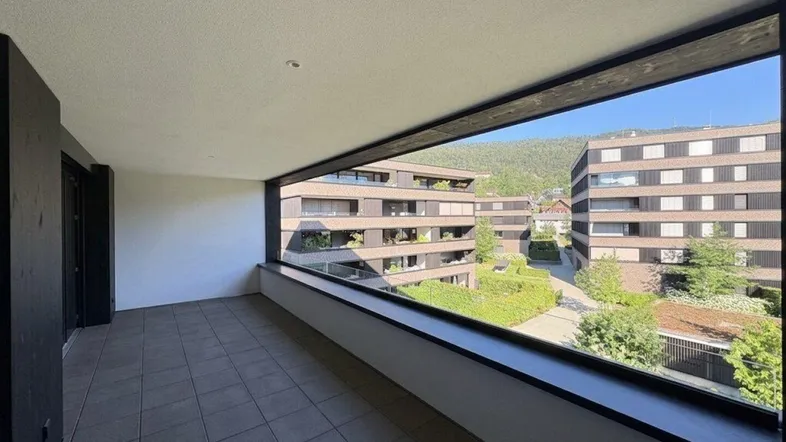 Geräumiger Balkon mit Fliesenboden und Blick auf die umliegenden Wohngebäude und Grünflächen.