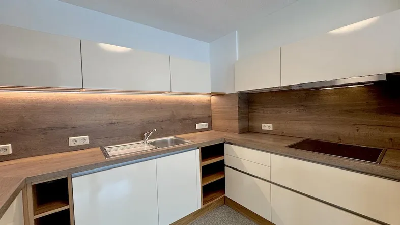 Moderne Einbauküche mit weißen Fronten, Holz-Arbeitsplatten und integriertem Kochfeld.
