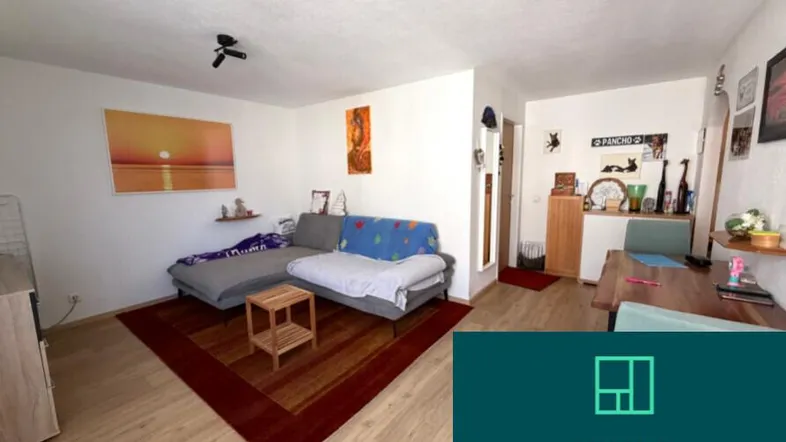 Heller Wohn- und Essbereich mit Sofa, Esstisch und Laminatboden, dekoriert mit Bildern und einem Teppich.