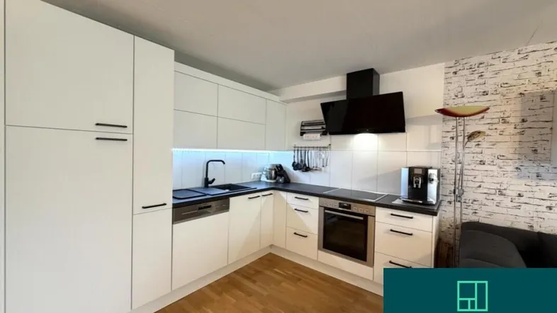 Moderne weiße Einbauküche mit dunkler Arbeitsplatte, integrierten Geräten und Holzfußboden.