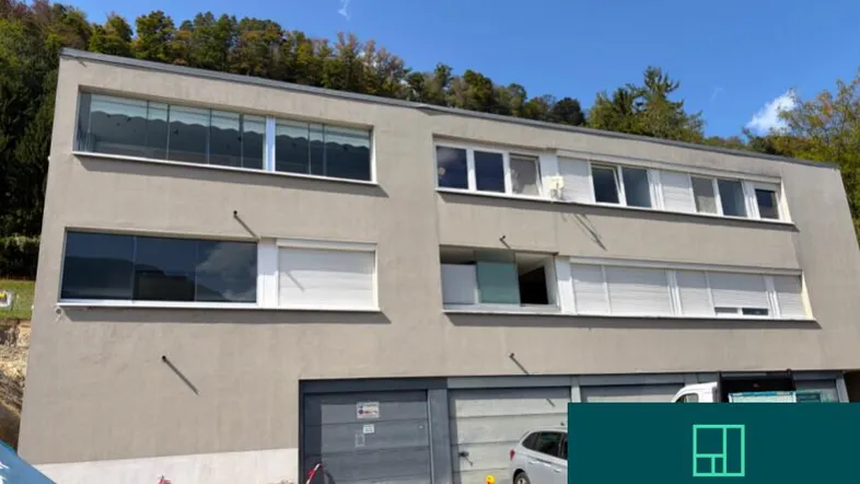 Modernes Mehrfamilienhaus mit Garagen im Erdgeschoss und Baustelle im Vordergrund.