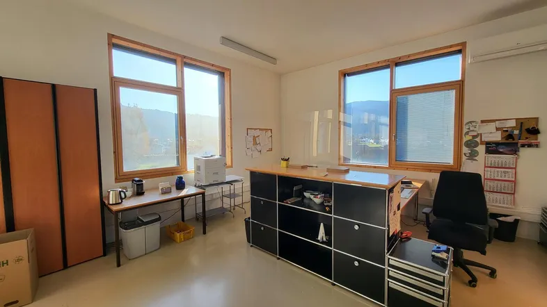 Modernes Büro mit funktionalen Möbeln und großen Fenstern, die den Raum mit natürlichem Licht durchfluten.