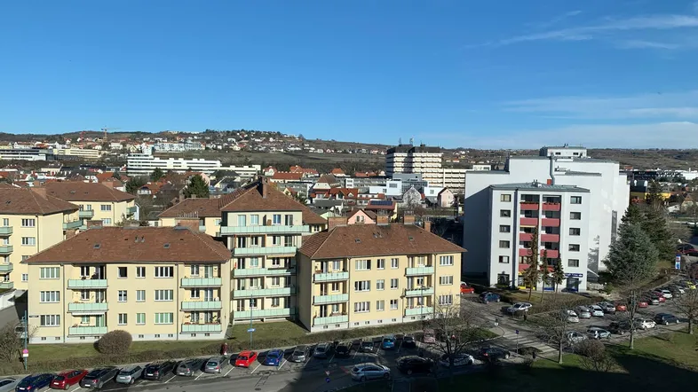 Panoramablick über eine Wohnsiedlung mit Mehrfamilienhäusern und grünen Flächen unter blauem Himmel.