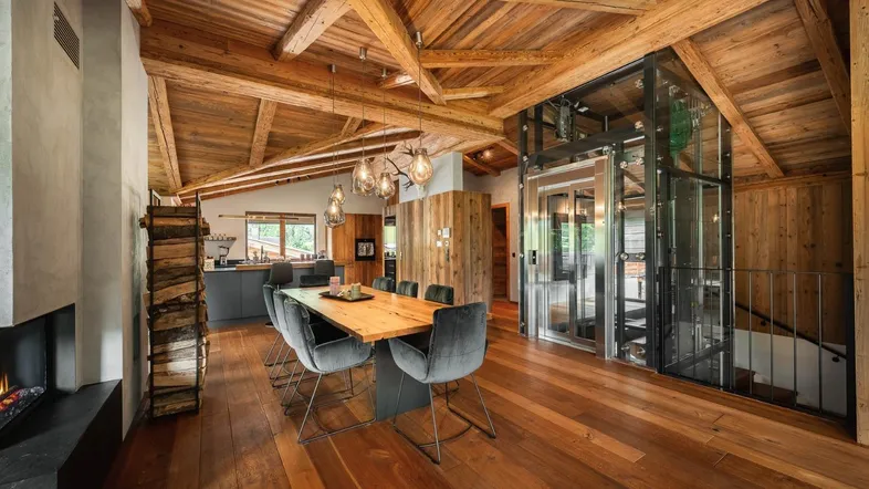 Heller Wohn-Essbereich mit Holzbalkendecke, integriertem Aufzug und moderner Einrichtung.