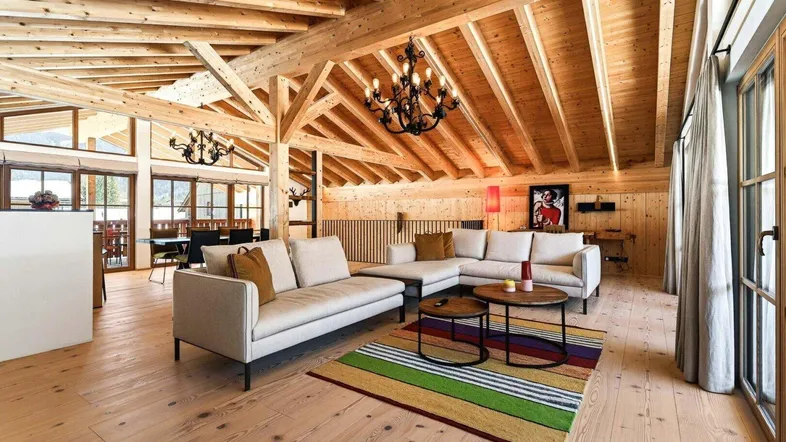 Gemütlicher Wohnbereich mit bequemen Sofas, Holzbalkendecke und farbenfrohem Teppich.