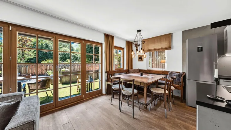 Gemütlicher Essbereich mit Holztisch, Eckbank und großen Fenstern zum Garten.
