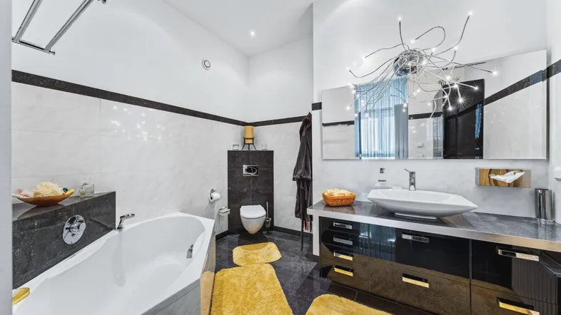 Modernes Badezimmer mit Badewanne, Einzelwaschbecken und dunklen Fliesenakzenten.