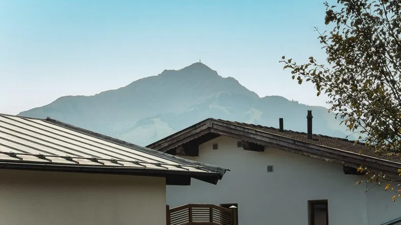 Blick auf die umliegende Berglandschaft über den Dächern der Häuser.