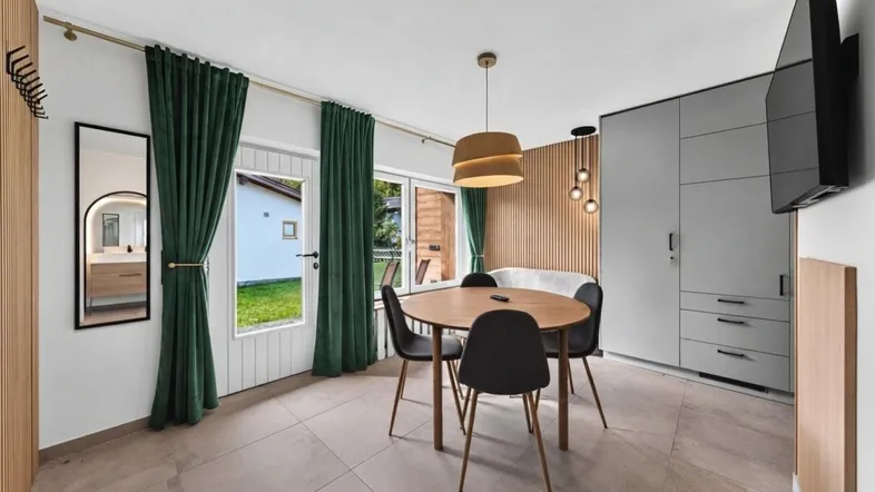 Moderner Wohn- und Essbereich mit Zugang zum Garten, Fliesenboden und integrierten Schränken.