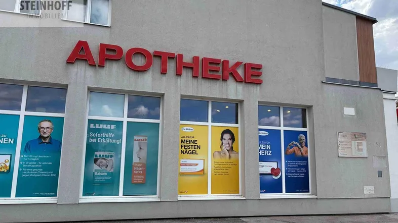 Fassade eines modernen Geschäftsgebäudes mit großen Schaufenstern und dem Schriftzug "APOTHEKE".