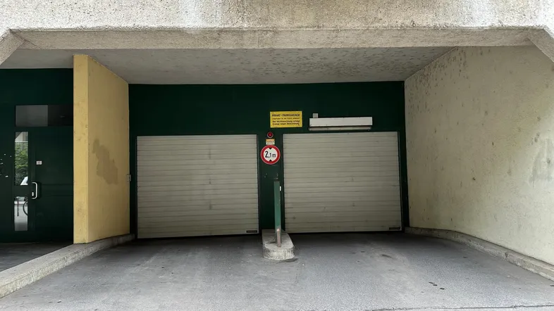 Eingang zu einer Tiefgarage mit zwei Rolltoren und einer Höhenbegrenzung von 2,1 Metern.