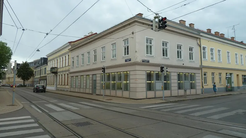 Gebäude an einer Straßenecke mit Geschäften im Erdgeschoss und Wohnungen darüber.