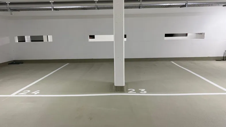 Helle Tiefgarage mit markierten Stellplätzen und sauberem Betonboden in neuwertigem Zustand.