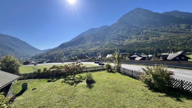 Weitläufiger Bergblick mit sonniger Landschaft und einer Straße im Tal.