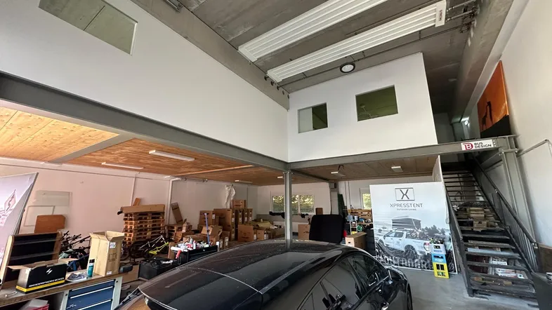 Großer offener Raum mit hoher Decke, Betonboden und einer Mezzanine-Ebene, ideal als Werkstatt oder Lager.